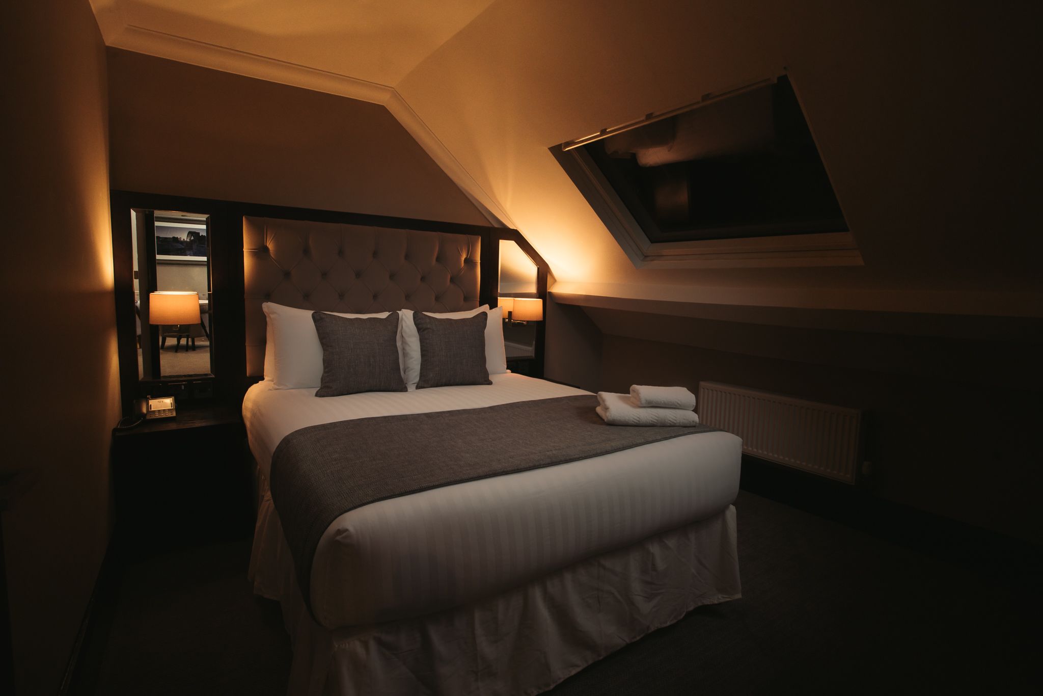 A hotel room with a large bed, a television mounted on the wall, and a window providing a view.