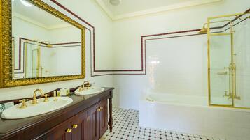 A bathroom with two sinks, a large mirror, and a bathtub.