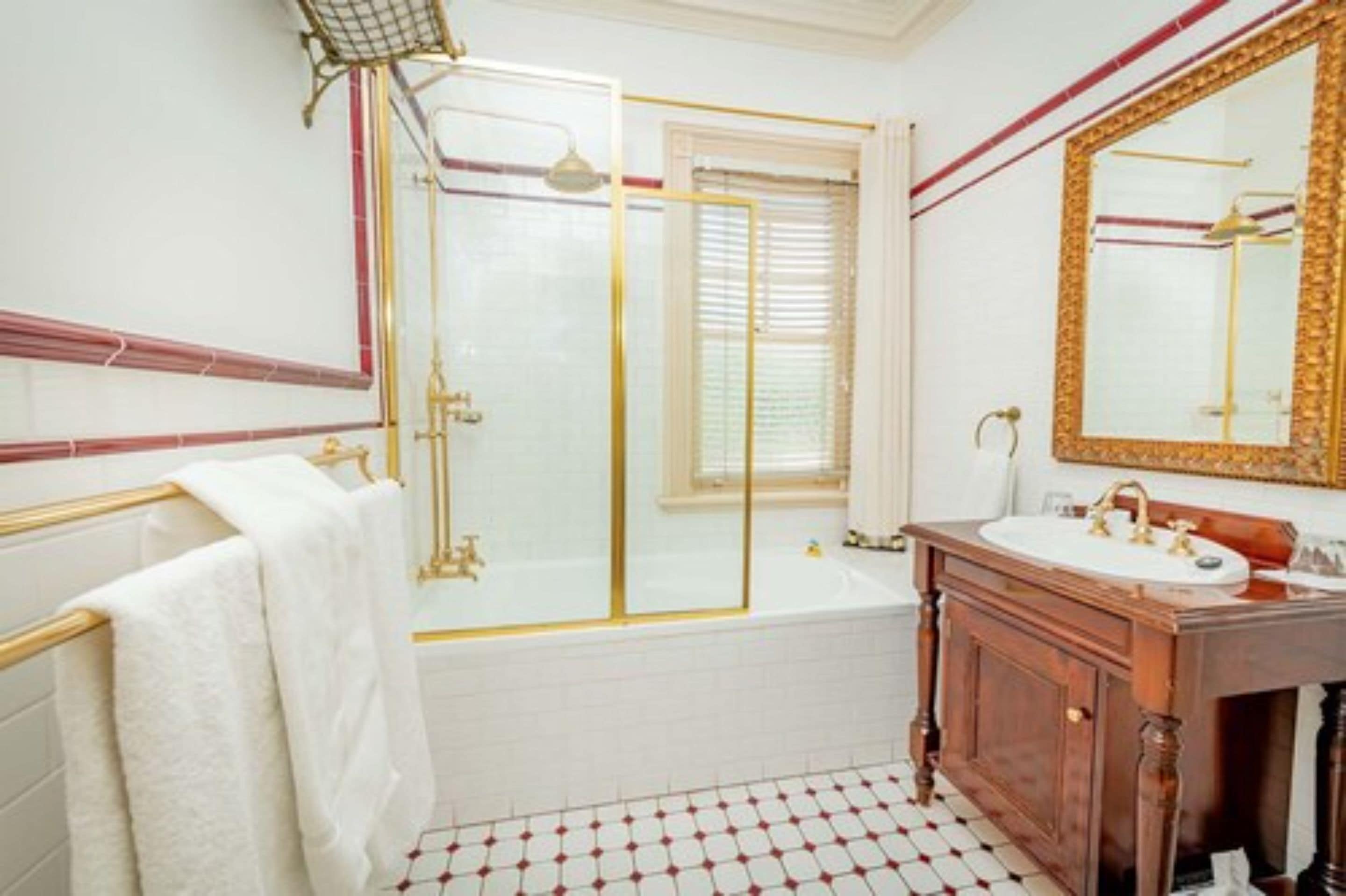 A bathroom with a white bathtub, a wooden vanity, a large mirror, and a shower enclosure.