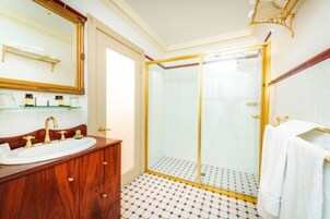 A bathroom with a wooden vanity, a white sink, a mirror, and a glass-enclosed shower.