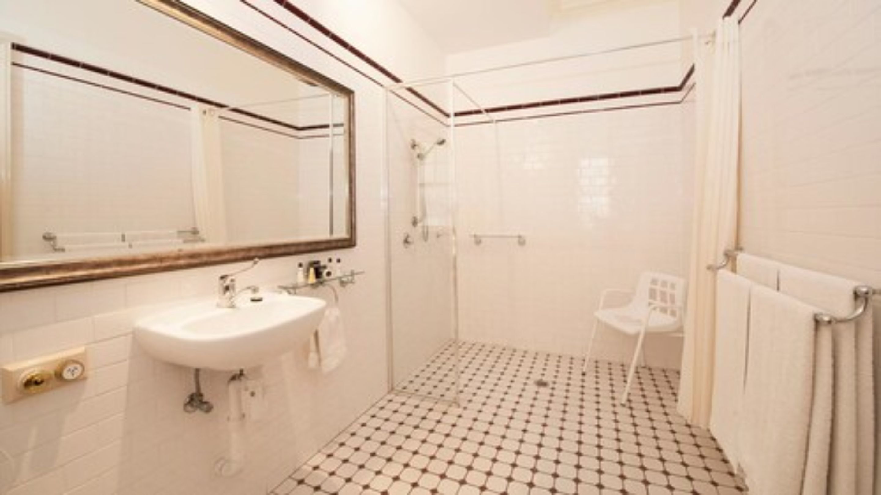Ein Badezimmer mit Waschbecken, Spiegel, Dusche und Fliesenboden.