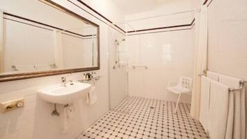 A bathroom with a sink, mirror, shower, and tiled floor.