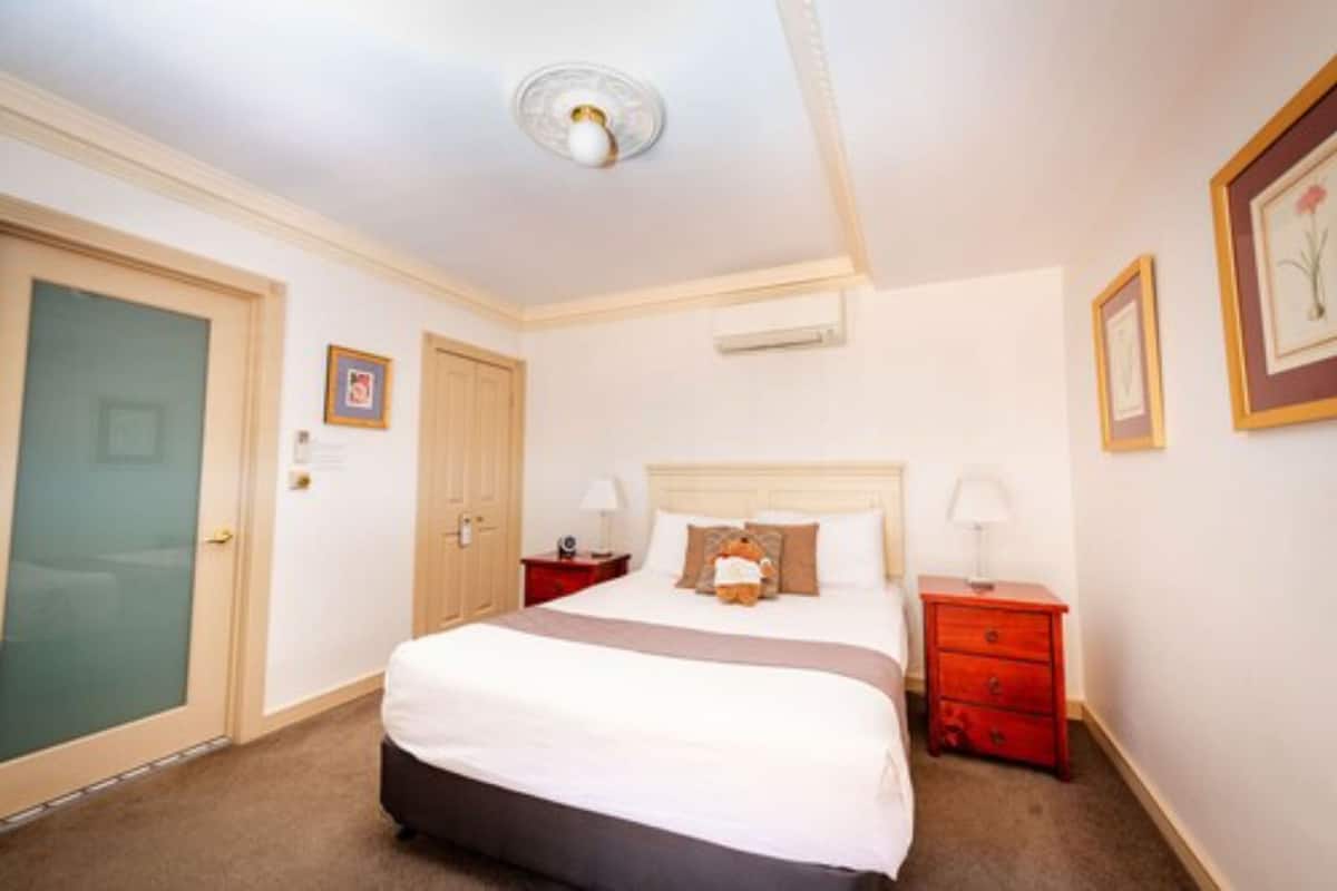 A hotel room with a large bed, a red nightstand, a wooden door, and a ceiling fan.