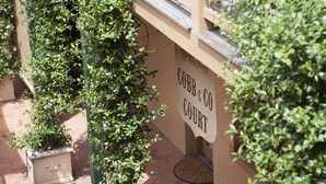 A building with a sign reading "Cobb & Co Court" and a brick pathway. - Cobb & Co Court Boutique Hotel (Mudgee)