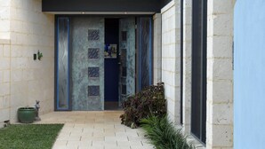 Een modern gebouw met een stenen gevel, een blauwe deur en een verharde entree met een kleine tuin.