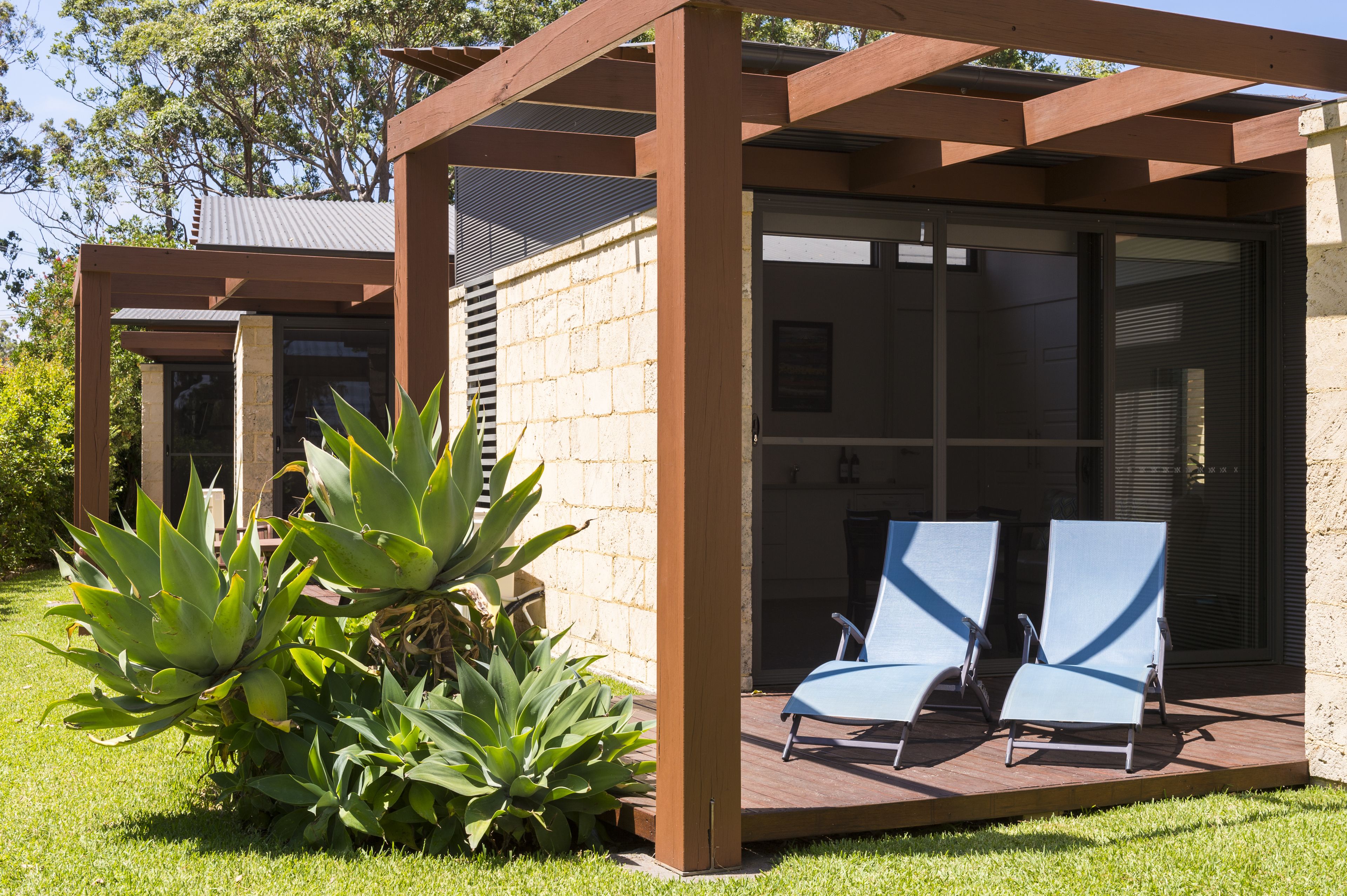 Et moderne udendørs opholdsområde med to loungesenge og en pergola.