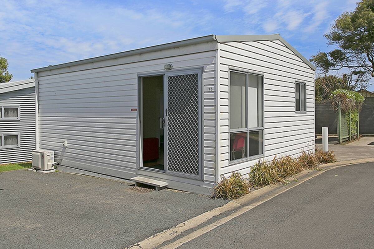 A single-story mobile home with a sliding door, a small porch, and a visible number '18' on the door.