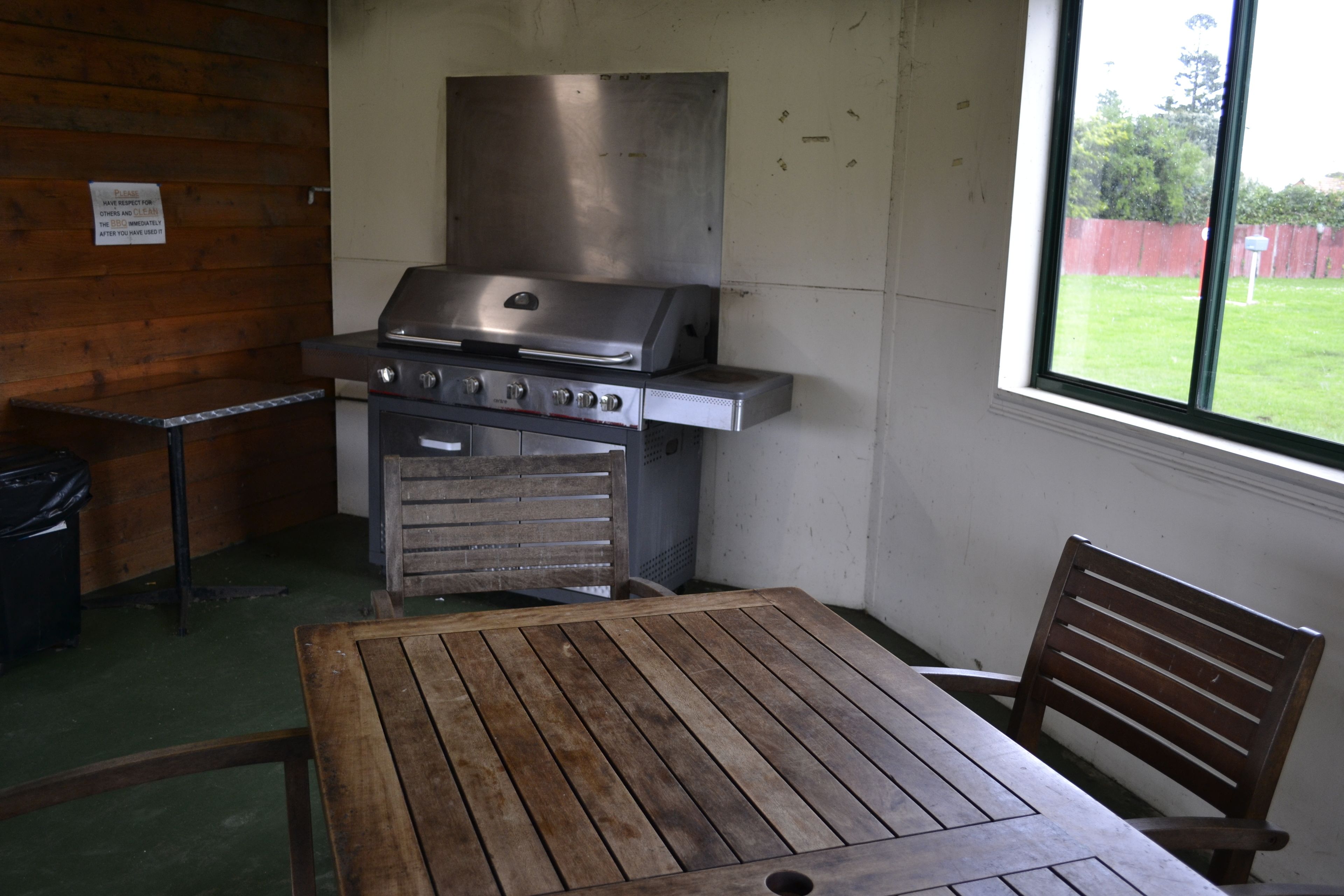 A kitchen with a stainless steel stove, a wooden table, and a window with a view of a yard.