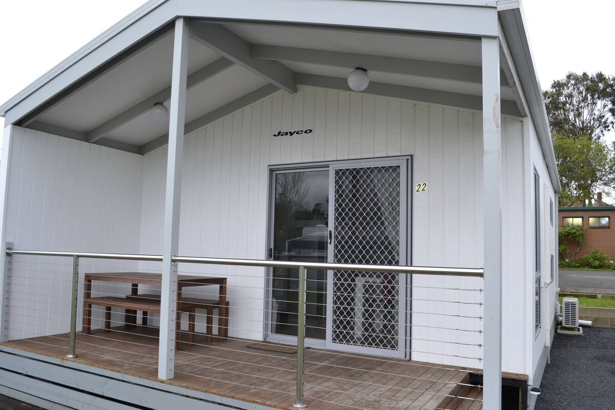 A white building with a covered porch, a bench, and a door marked "22".