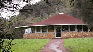 A stone building with a red roof, a covered porch, and a paved walkway leading to the entrance. - Victoria House (Portland)