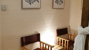 A room with two wooden chairs and a small table, a white curtain, and two framed fish paintings on the wall. - Arcadia House (Byron Bay)