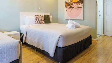 A neatly made bed with a white quilt, a pillow, and a rolled towel on the side.