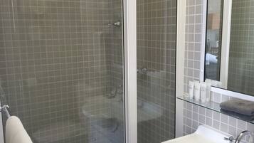A modern bathroom with a glass-enclosed shower, a white sink, and a mirror above it.