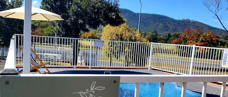 Una piscina al aire libre, sillones reclinables de piscina