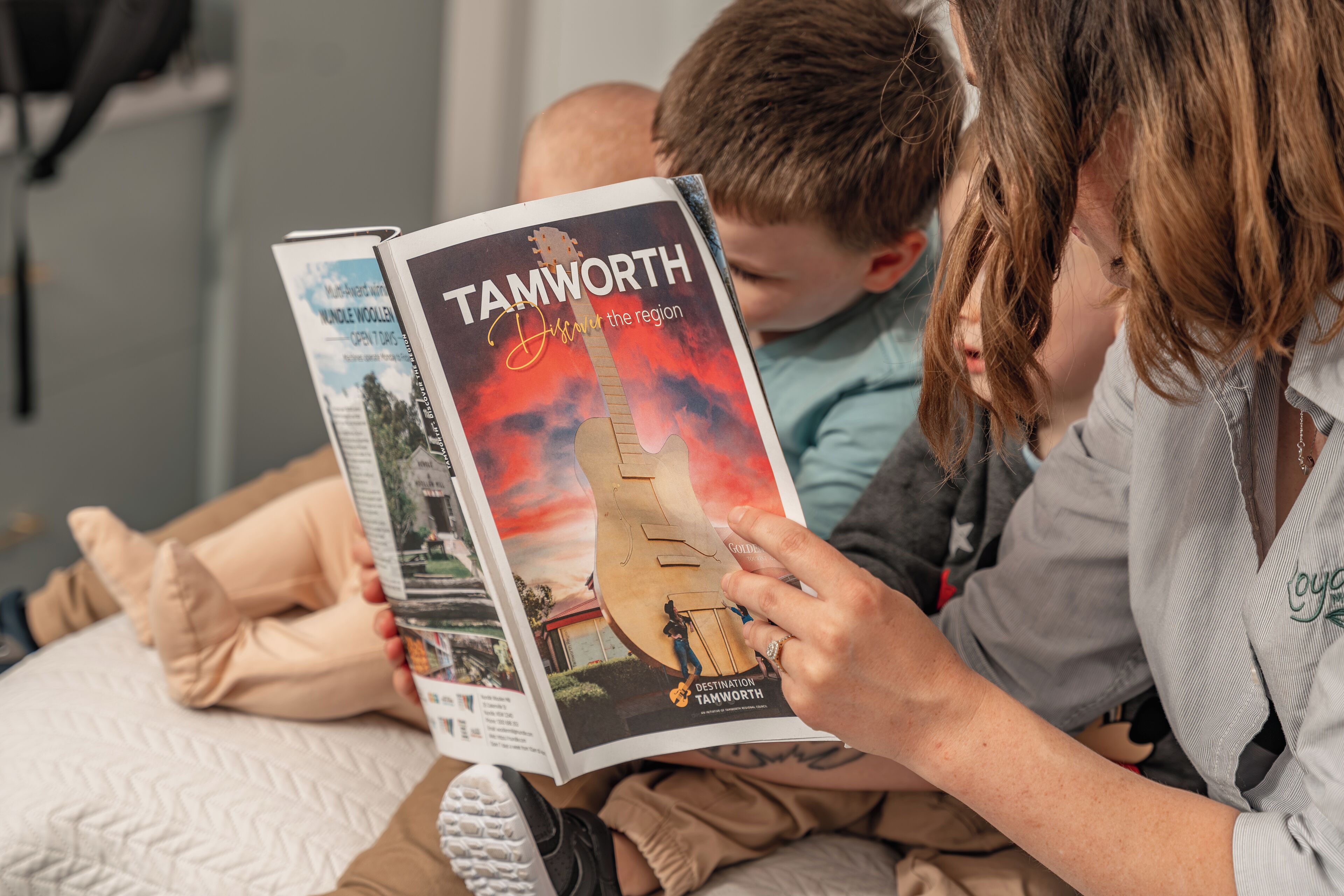 En person læser en rejseguide med titlen 'Tamworth Destination Tamworth'.