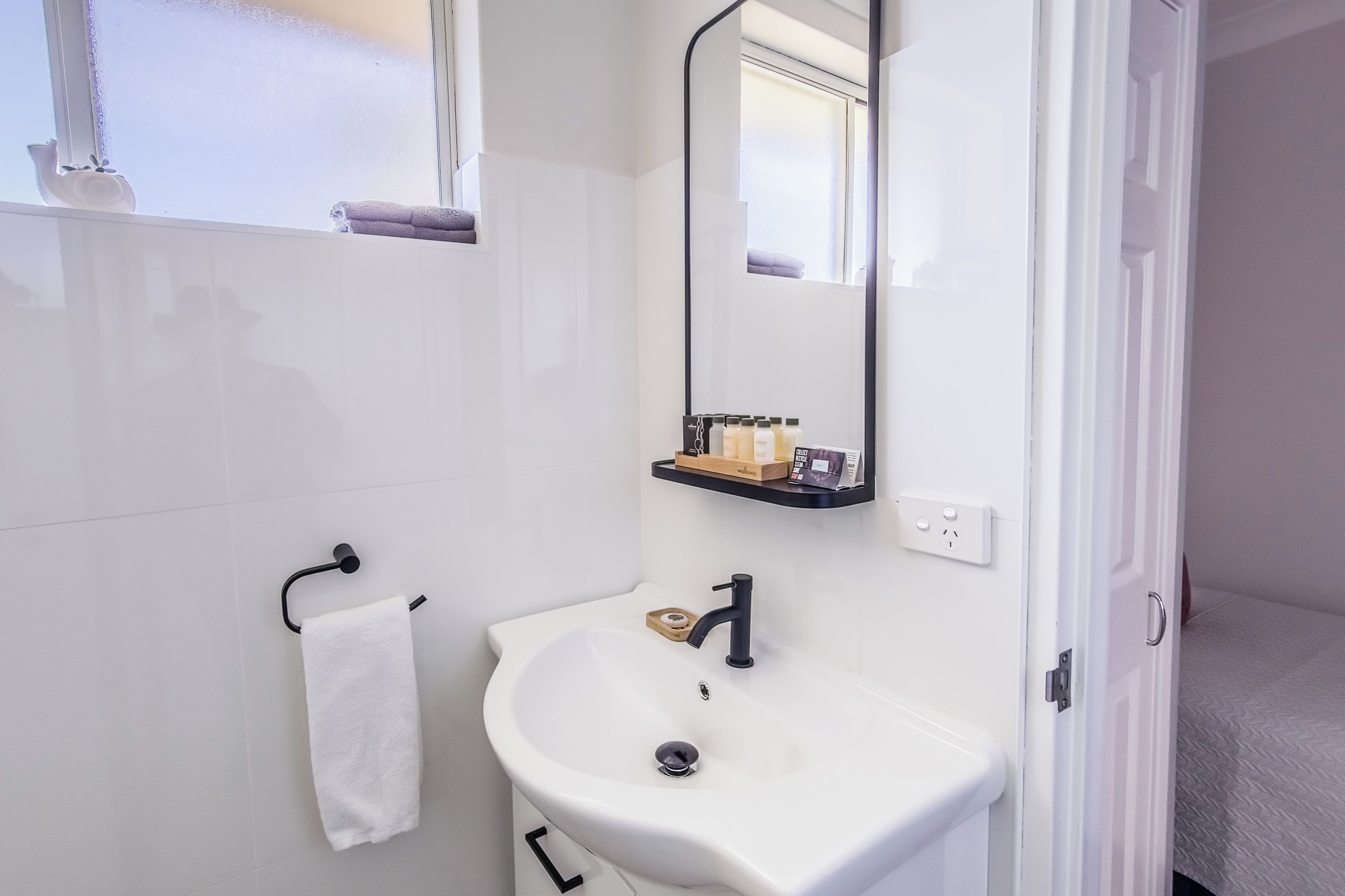 Une salle de bain avec un lavabo blanc, un miroir et un porte-serviettes.