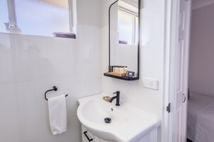 Une salle de bain avec un lavabo blanc, un miroir et un porte-serviettes.