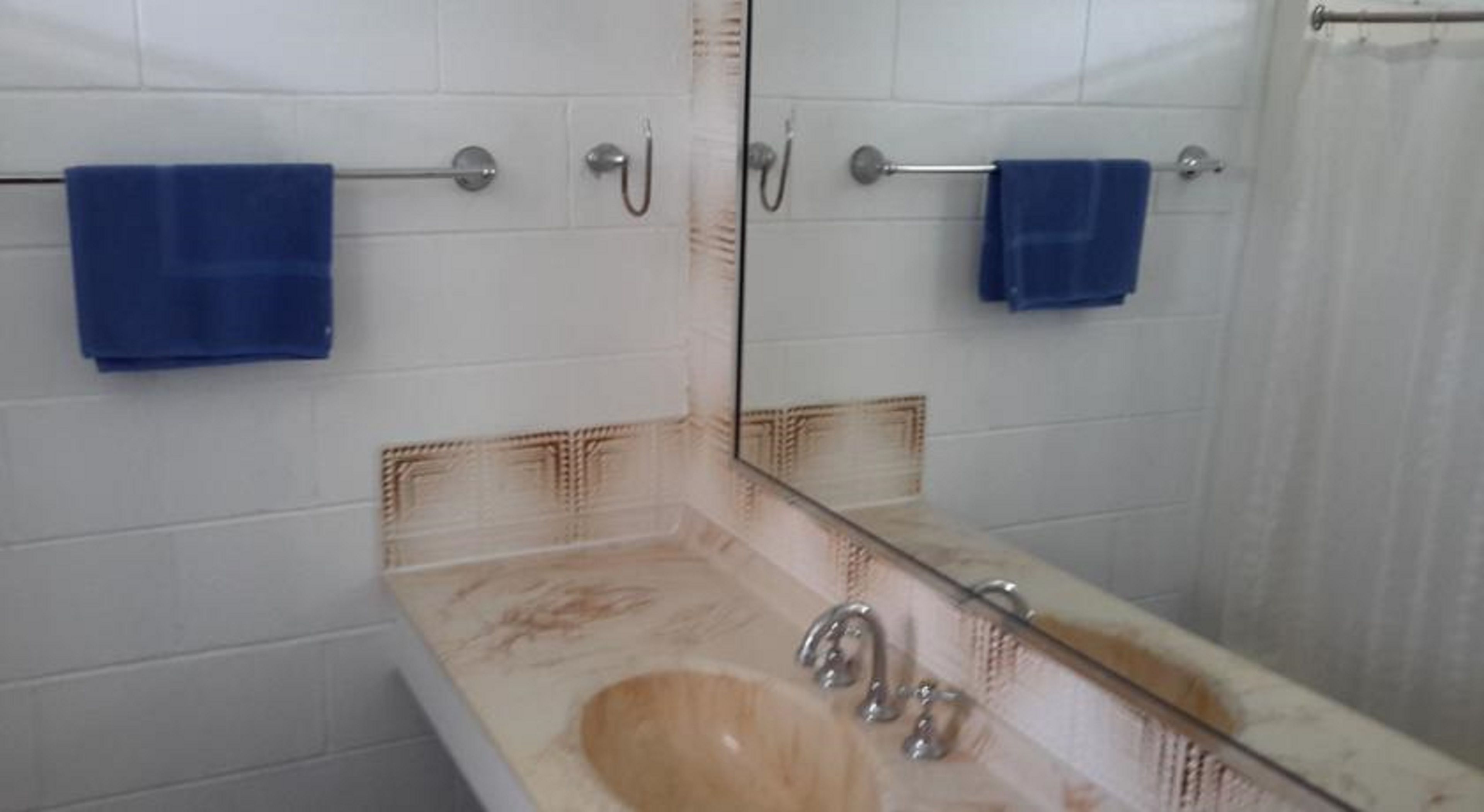 Une salle de bain avec un lavabo beige, un miroir et deux serviettes bleues suspendues à des porte-serviettes.