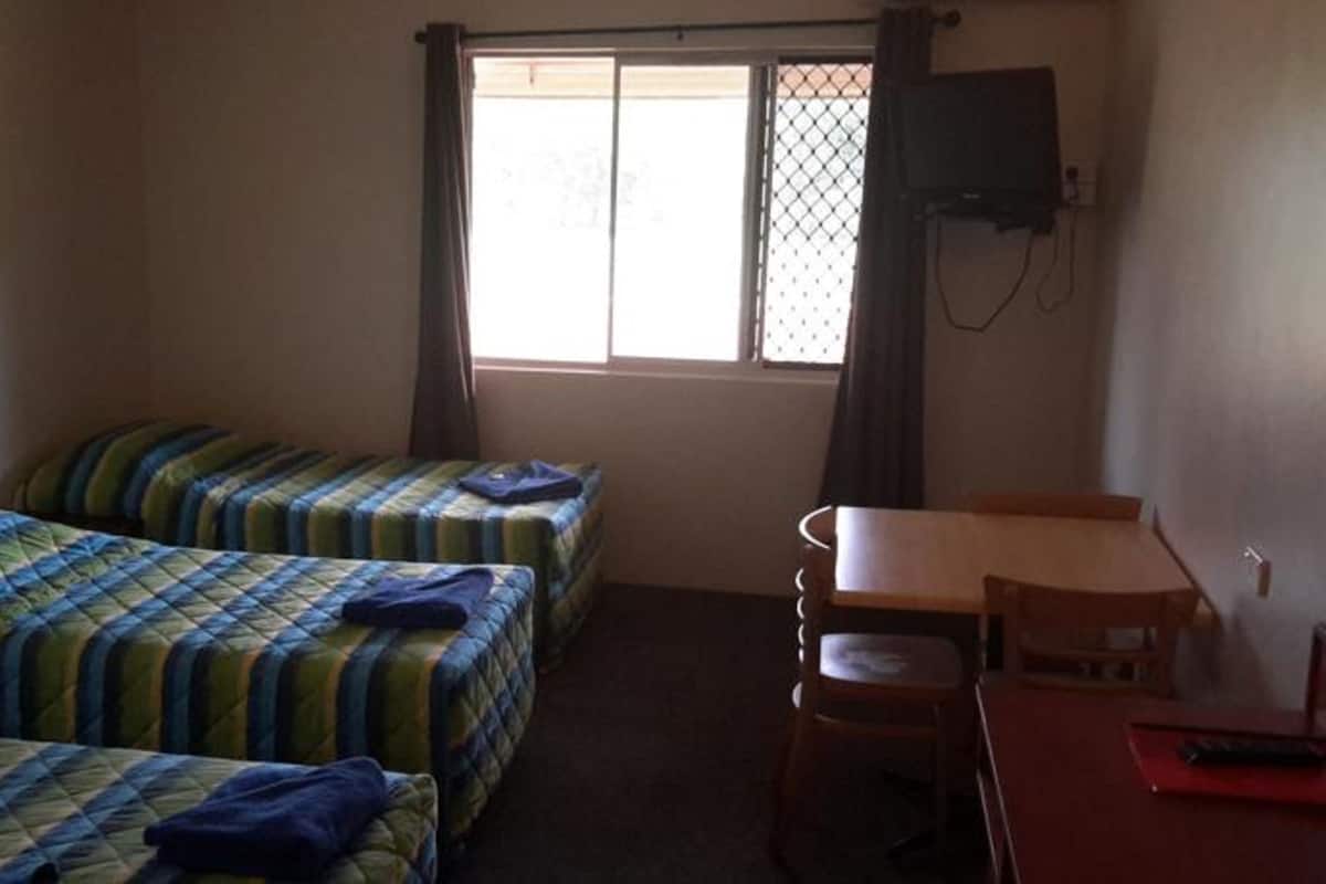 A room with two beds, a desk, a chair, and a TV.