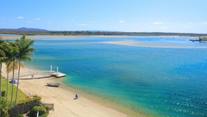 Une plage avec une eau turquoise et limpide, un rivage sablonneux et quelques bateaux.