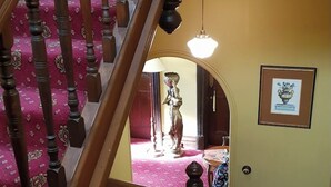 A wooden staircase with a red carpet leading to a room with a door and a framed picture on the wall. - The Manse (Daylesford)