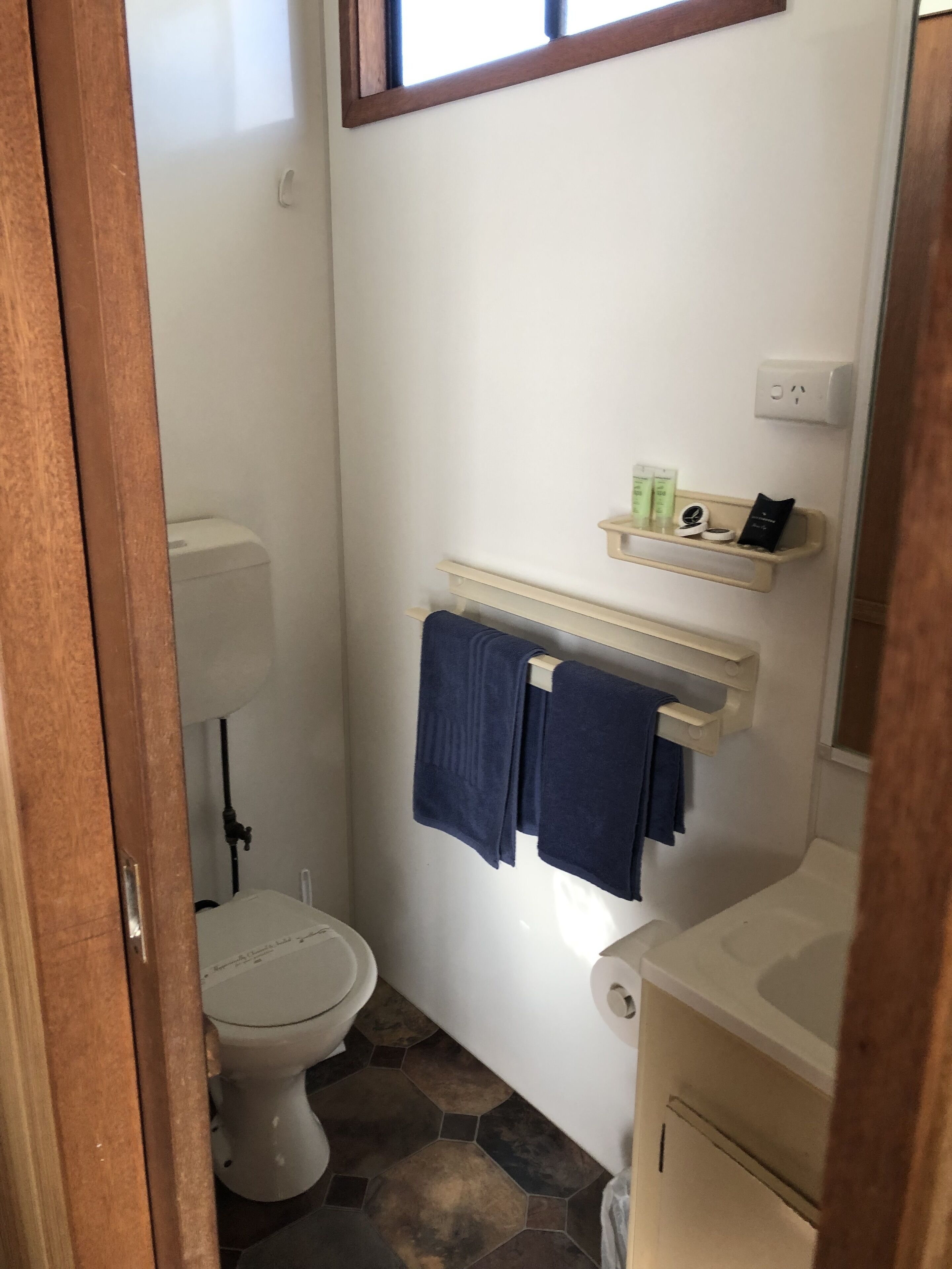 A compact bathroom with a toilet, a sink, and a towel rack.