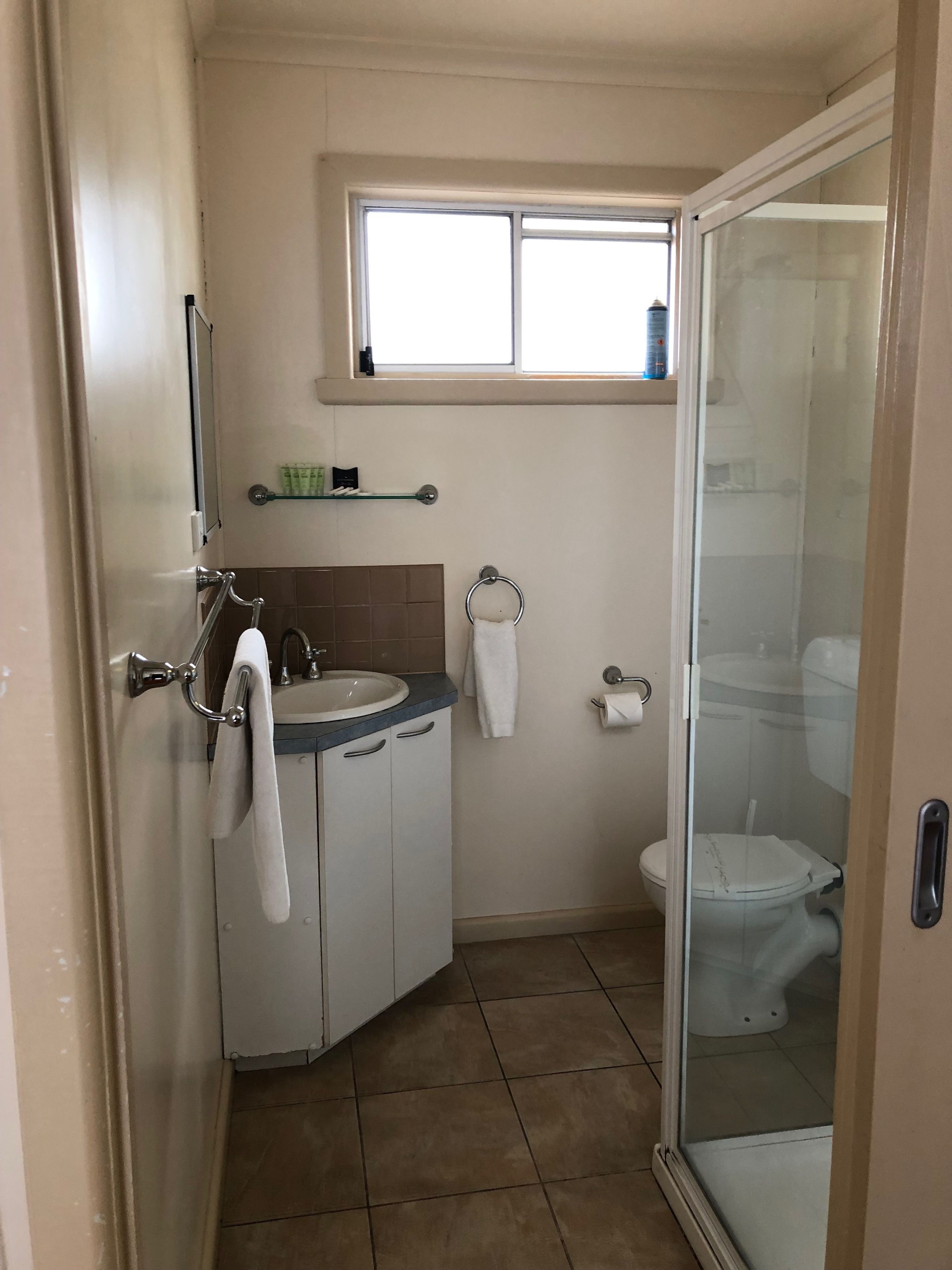 A bathroom with a sink, mirror, towel rack, toilet, and a shower area.