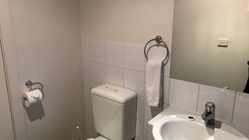 Un baño con inodoro, lavamanos y toallero.