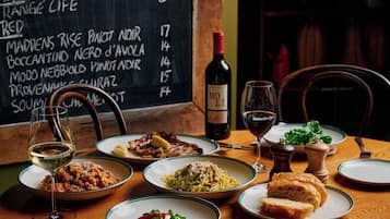 A restaurant table with various dishes, wine glasses, and a menu board.