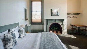 A bedroom with a bed, a fireplace, a dining table, and a window with blinds.