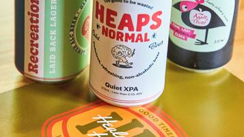 Three cans of beer on a table with a coaster.