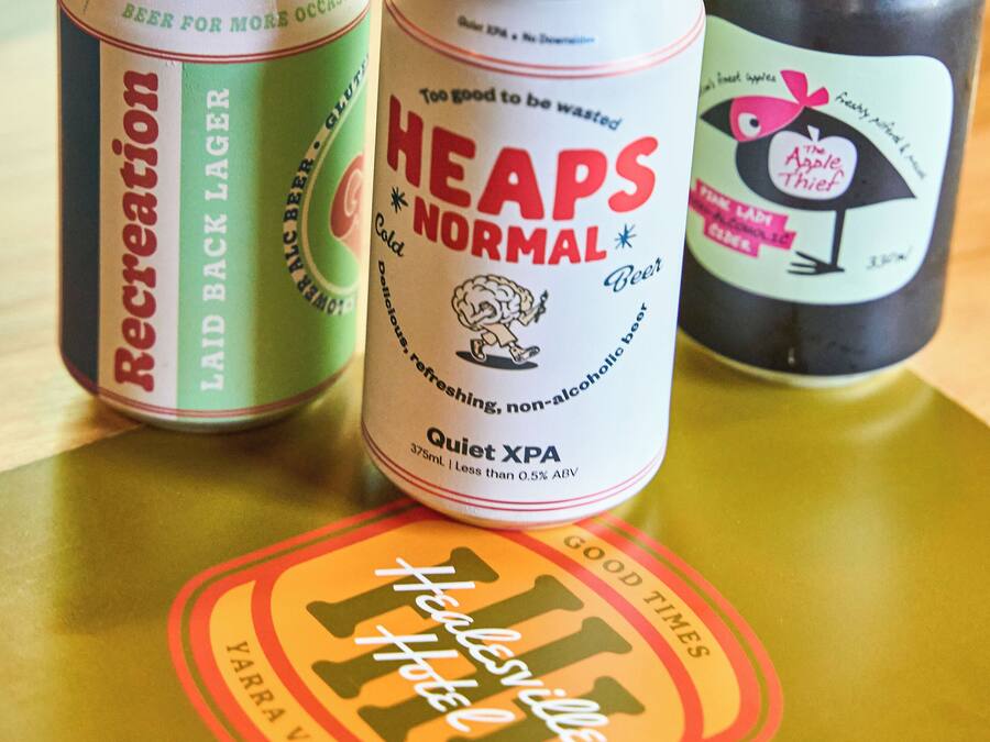 Three cans of beer on a table with a coaster.