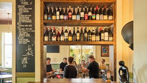 A bar with a wooden shelf displaying various wine bottles.