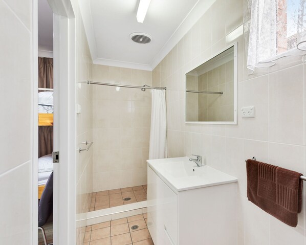 A modern bathroom with a shower, toilet, and sink. - Fossicker Caravan Park (Glen Innes)