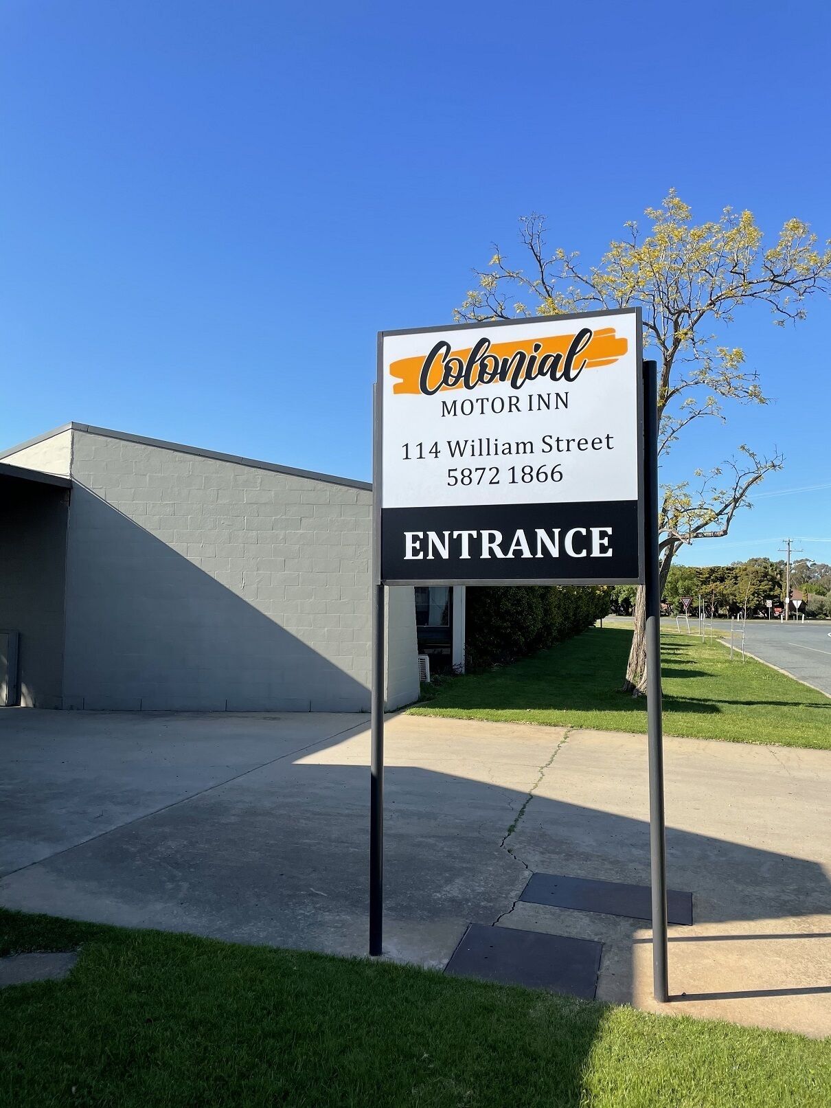 A sign for Colonial Motor Inn at 114 William Street with an entrance sign.