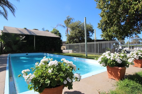 Una piscina al aire libre, sillones reclinables de piscina