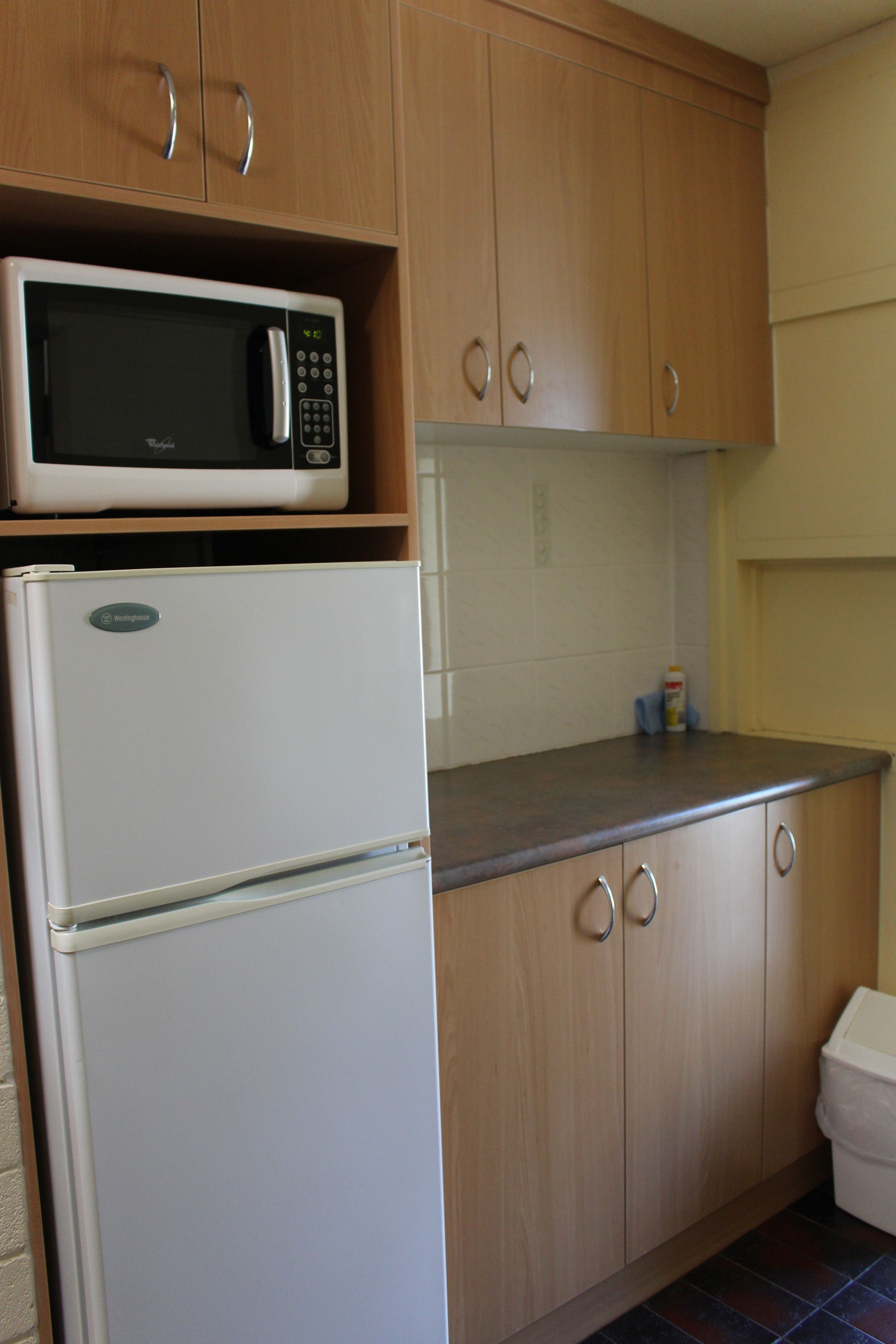 Una cocina con armarios de madera, un refrigerador blanco y un microondas encima.