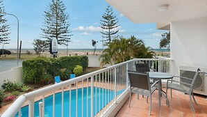 A balcony with a pool, outdoor furniture, and a view of the beach and trees. - Meridian Tower (Coolangatta)