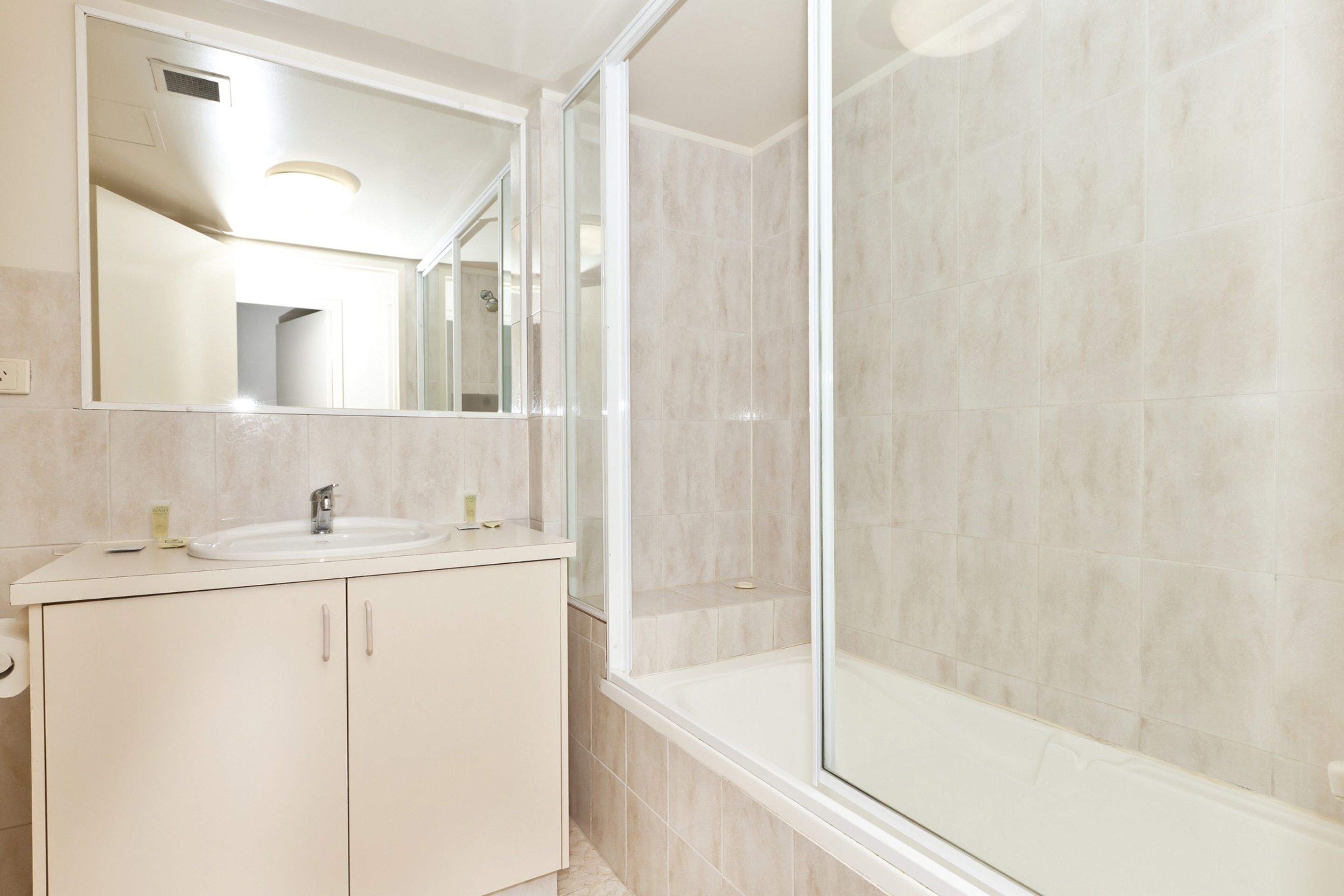 A bathroom with a sink, mirror, and shower.
