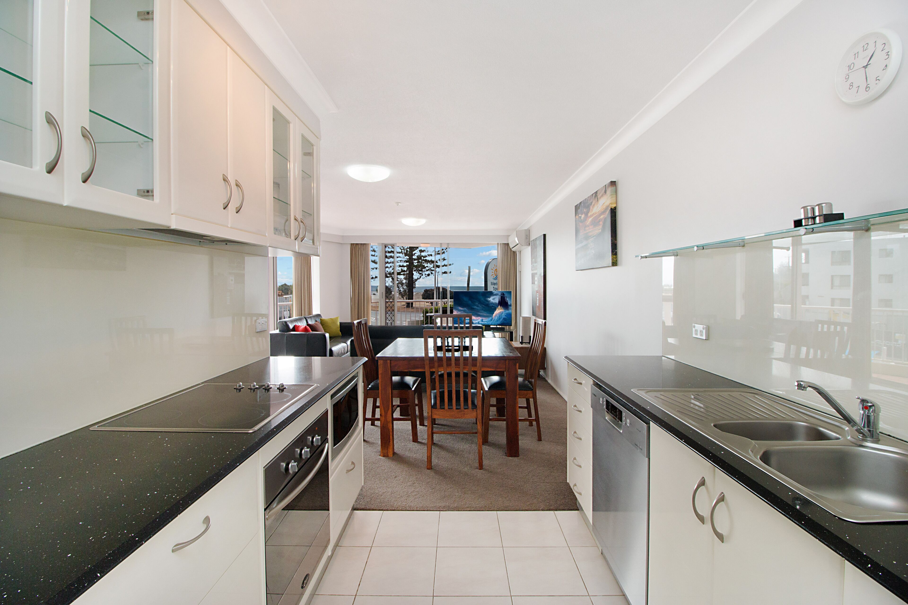 A modern kitchen with a dining area, featuring a large island, built-in appliances, and a view of the outdoors.