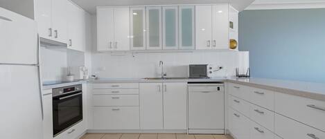 A modern kitchen with white cabinetry, a built-in oven, and a dishwasher.
