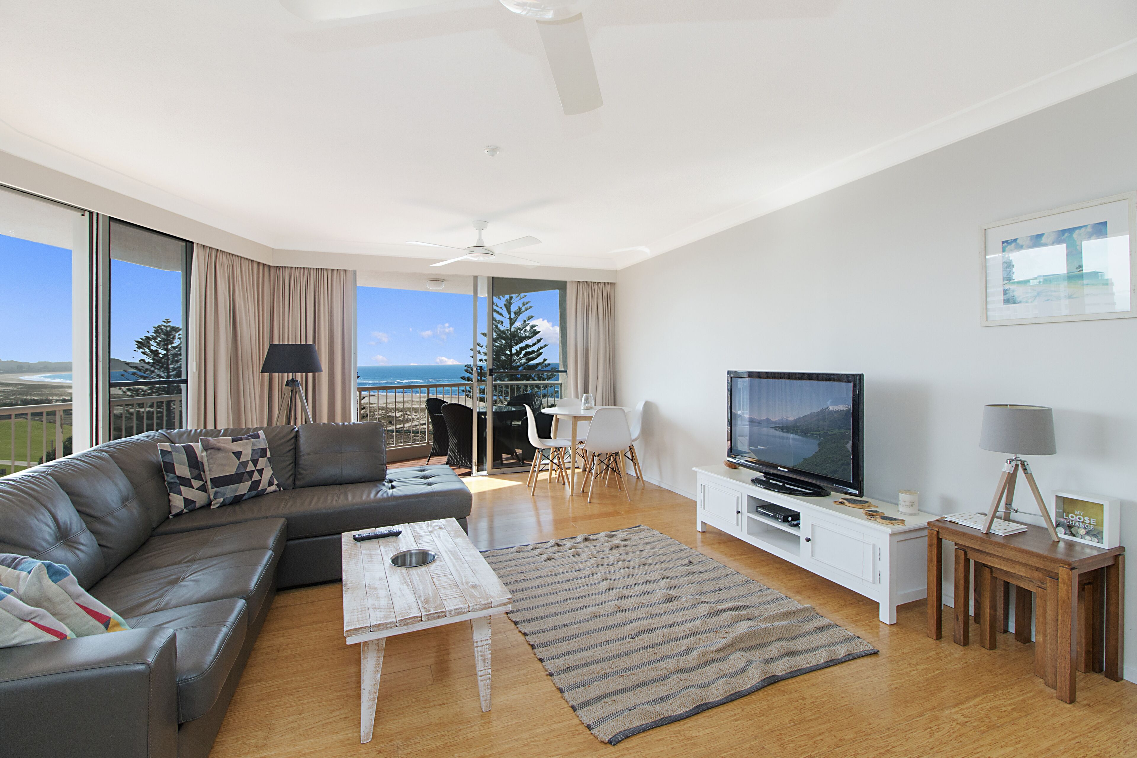 Uma sala de estar moderna com sofá, televisão e área de jantar.