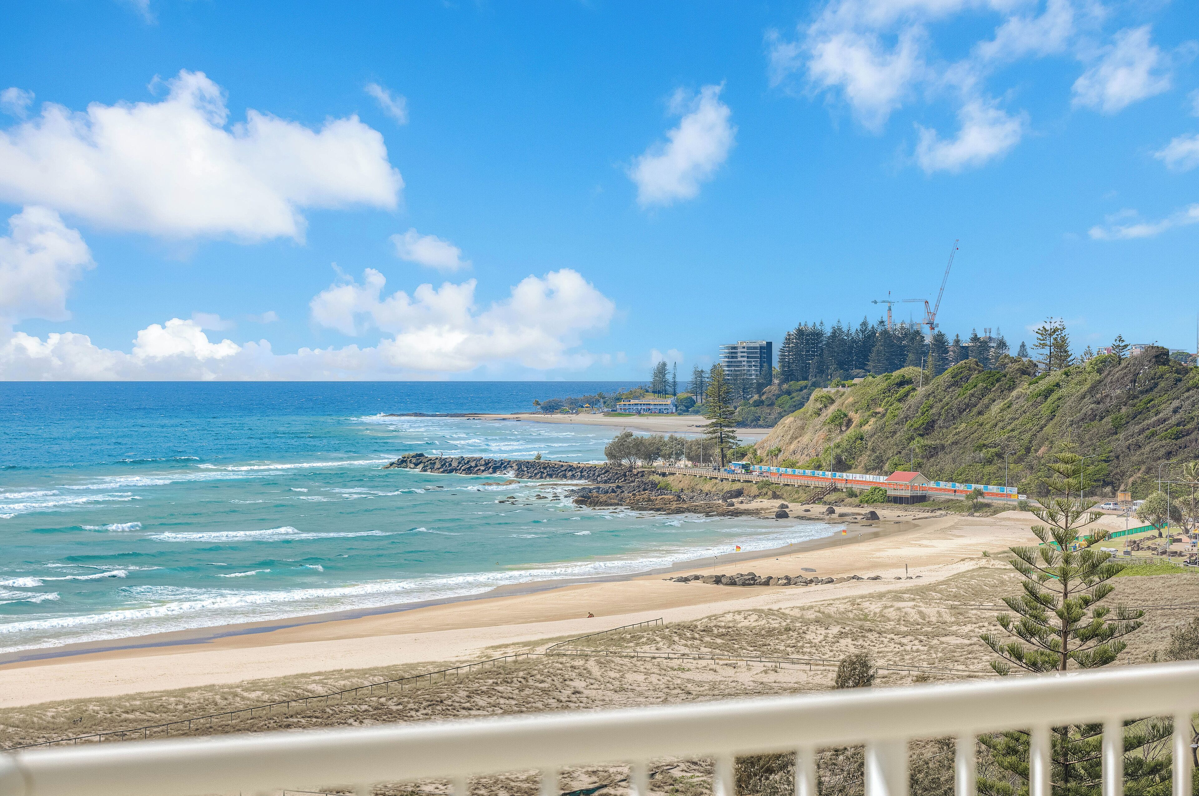A beach with a view of the ocean and a train track.