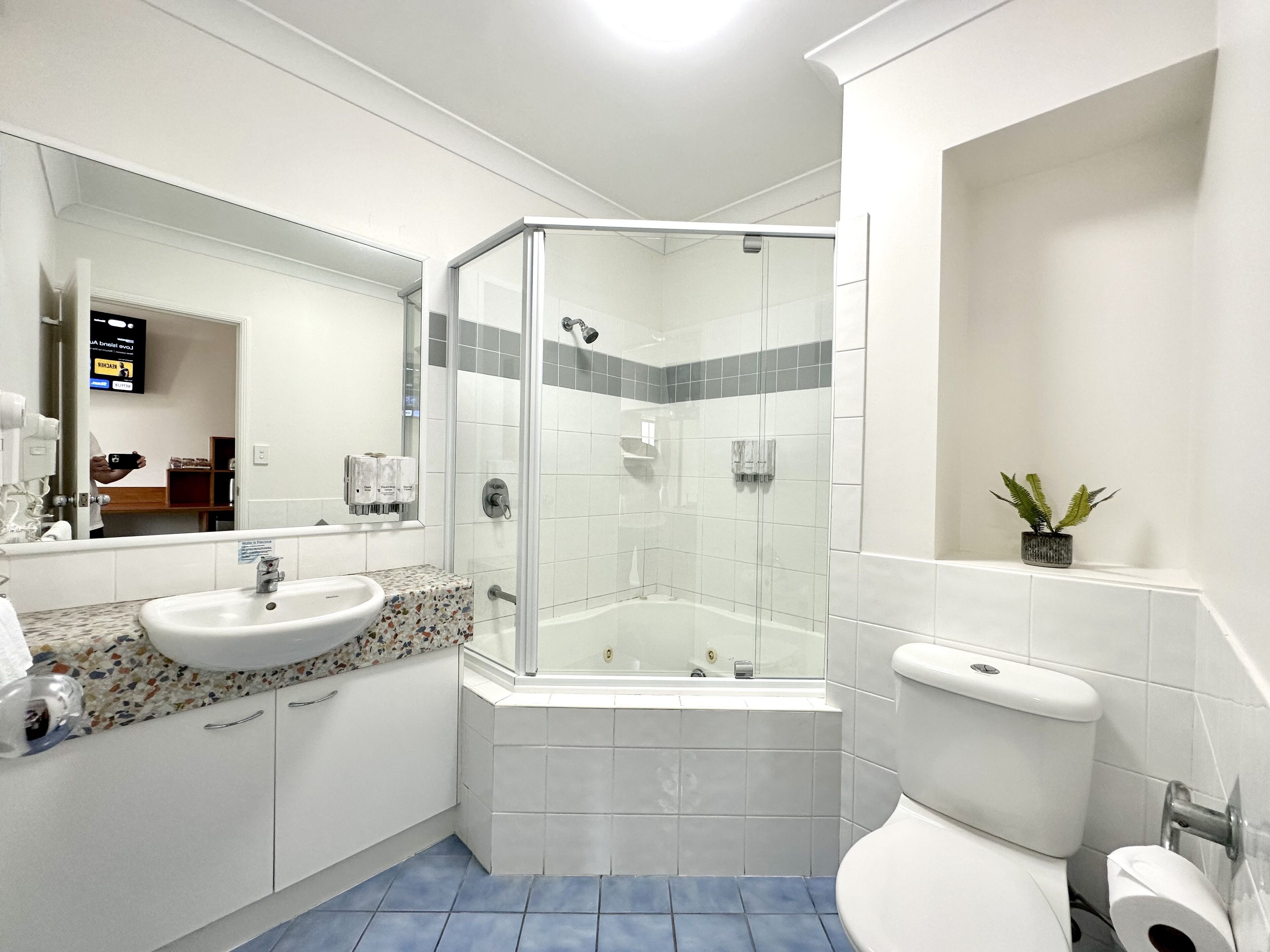 Un baño moderno con ducha de vidrio, bañera independiente, lavamanos con encimera decorativa y un inodoro.