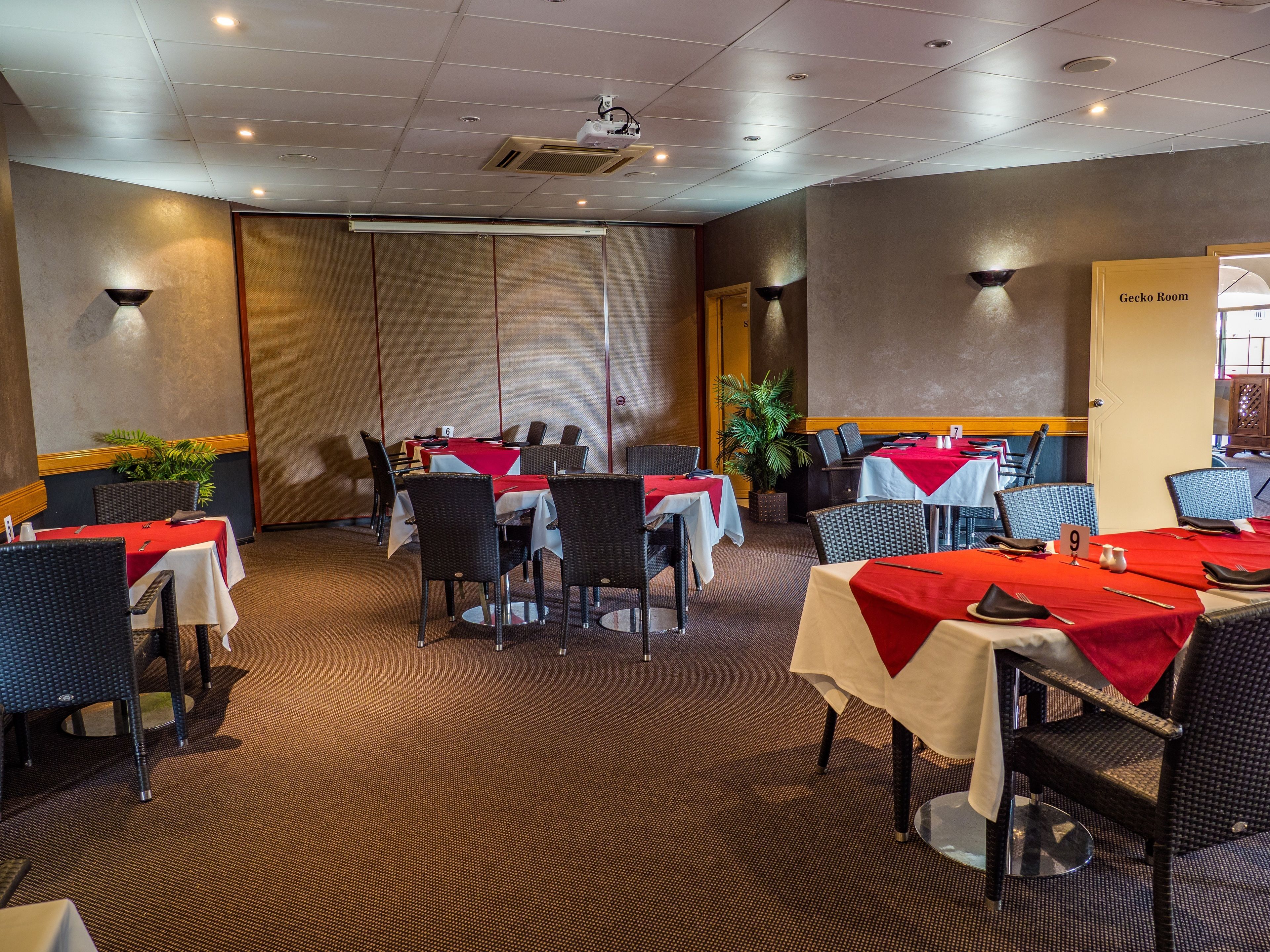A conference room with tables set for meetings, equipped with chairs and a projector.