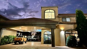 Un hotel con una entrada cubierta, un amplio ventanal de arco y un cartel que indica el timbre nocturno.