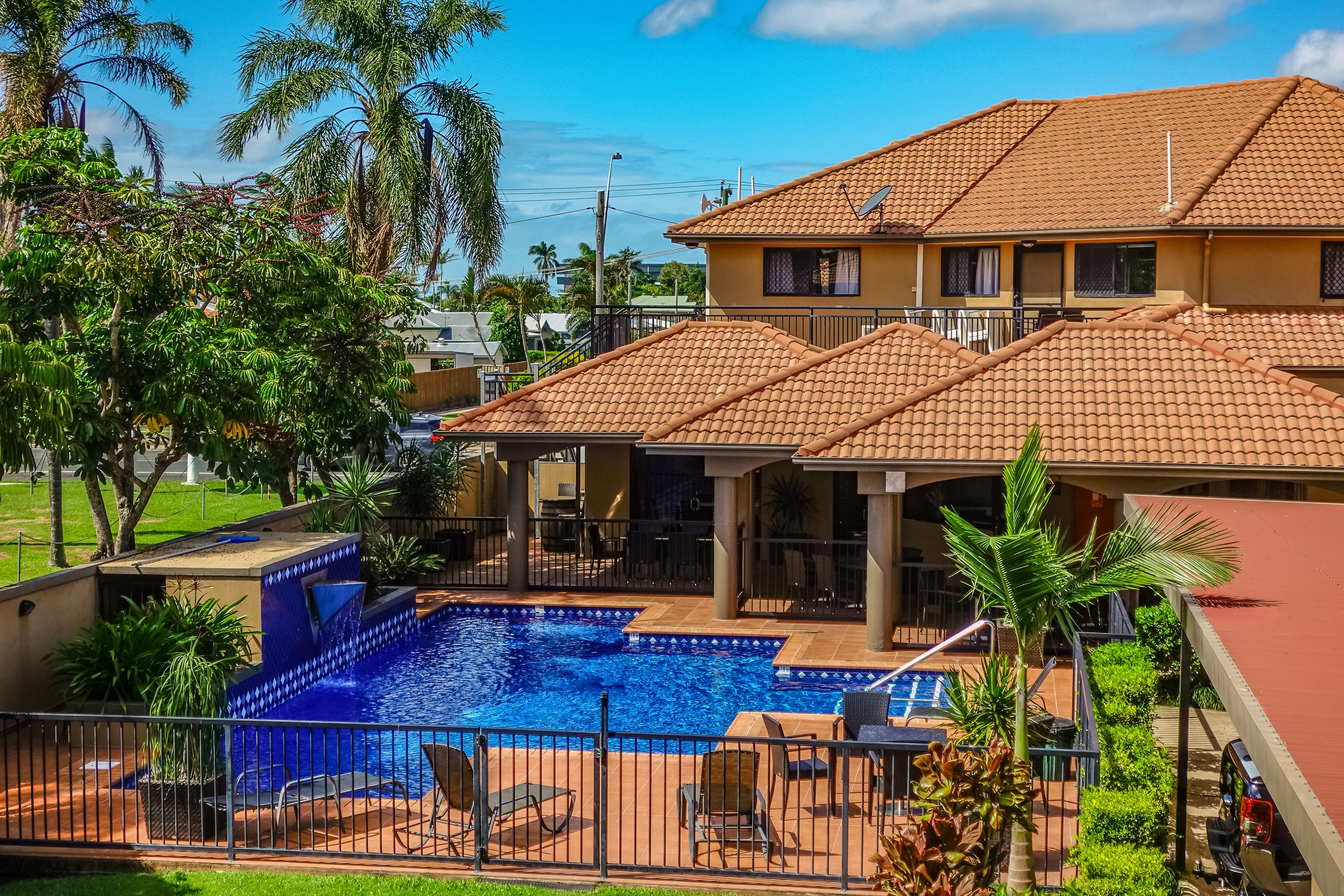 A two-story building with a swimming pool, outdoor seating, and a covered patio area.