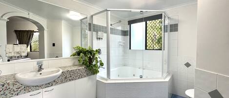 Une salle de bain moderne avec une baignoire sur pieds, une douche à parois de verre et un comptoir en granit avec un évier.