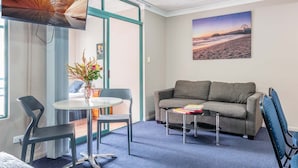 A living room with a sofa, a coffee table, and a TV mounted on the wall. - Albion Manor (Albion)