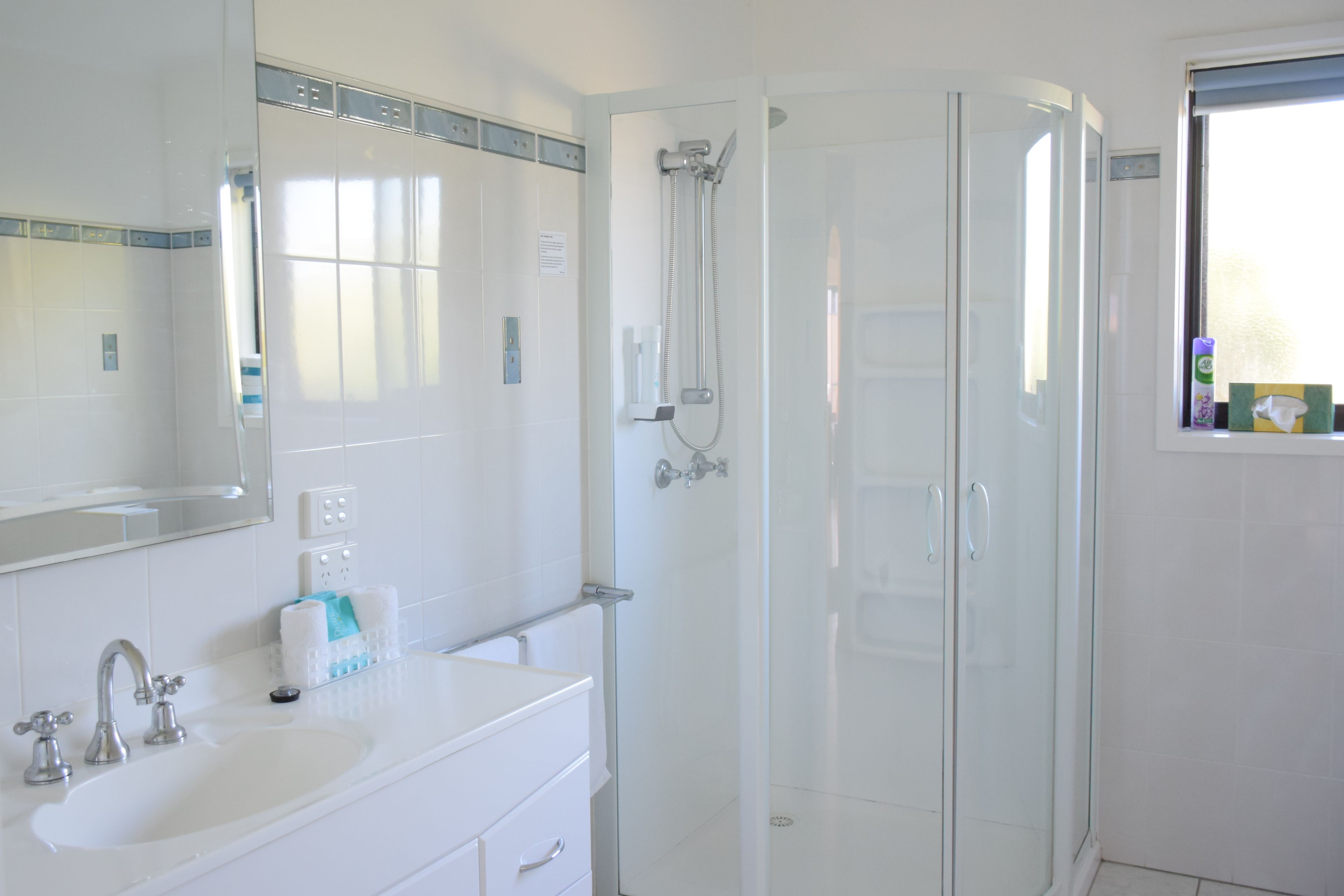 A modern bathroom with a glass-enclosed shower, a white sink, and a mirror above the sink.